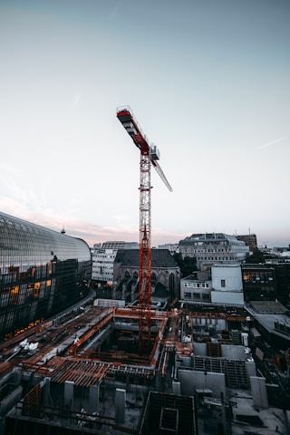 A modern crane lifting heavy materials at a busy construction site during sunset.
