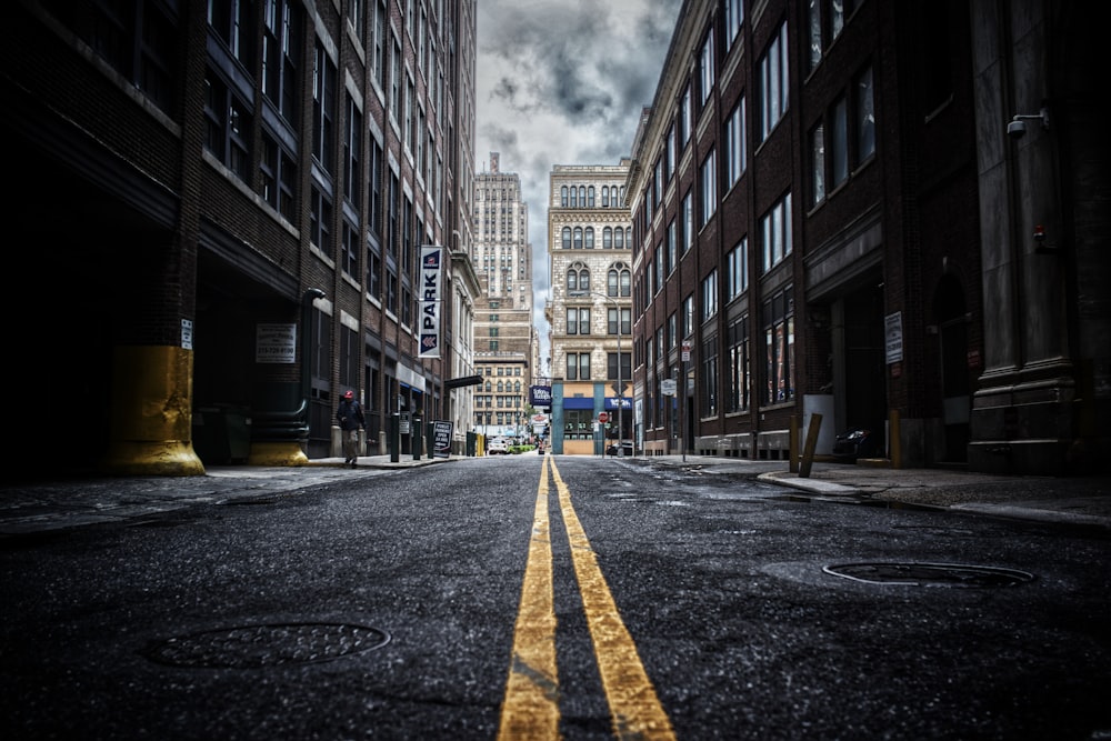 low-angle photo of street between two brown concrete buildings