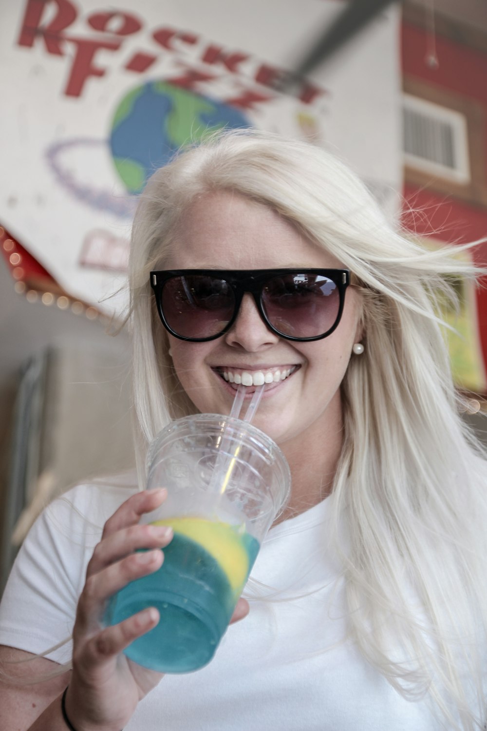 smiling woman in white shirt zipping from cup