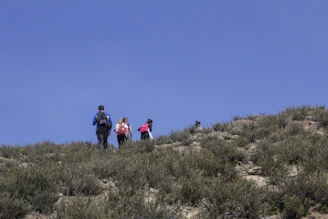 A group of adventurers hiking up a mountain under a clear blue sky.