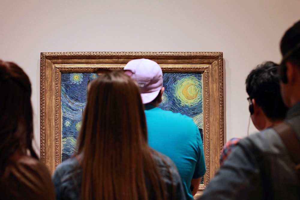 people looking on Starry Starry Night painting with brown frame