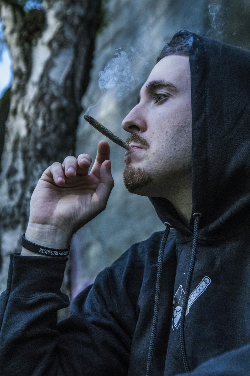 man in black hoodie using brown joint, celebrating 4/20 in quarantine 