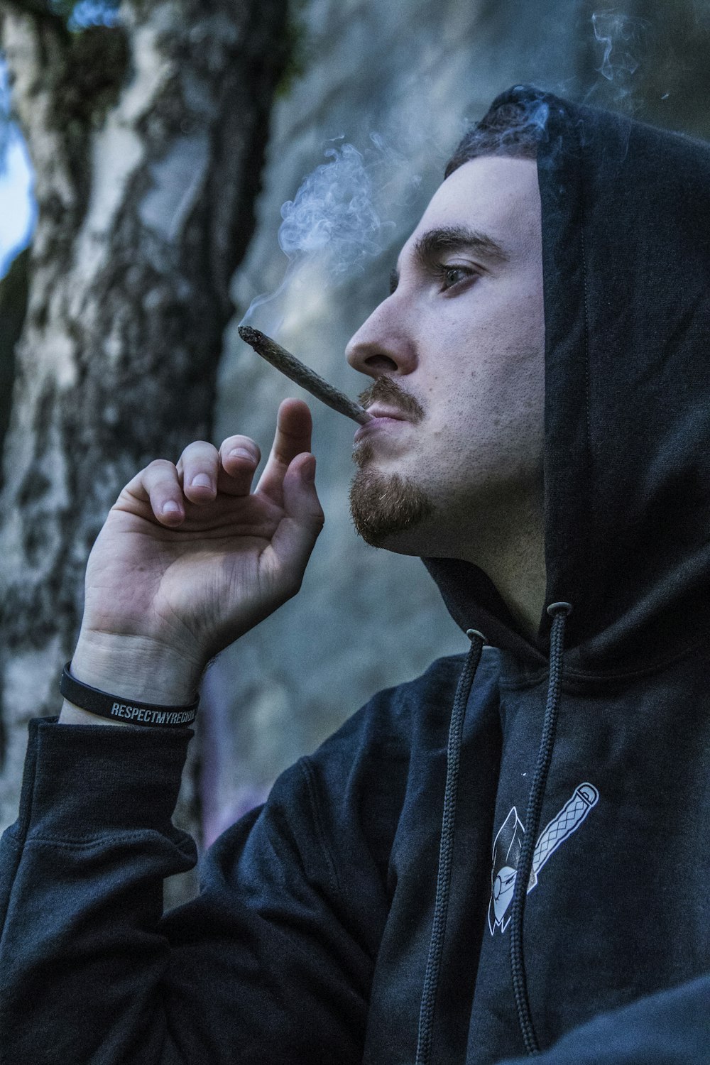 man in black hoodie using brown joint