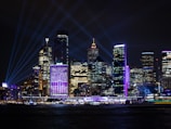 Modern city skyline at night with illuminated buildings connected by vibrant digital lines in signal violet.