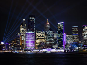 A vibrant city skyline at night illuminated with colorful architectural lighting.