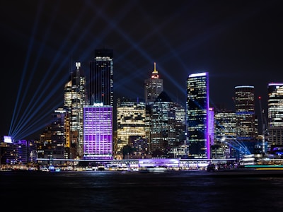 Modern city skyline at night with illuminated buildings connected by vibrant digital lines in signal violet.