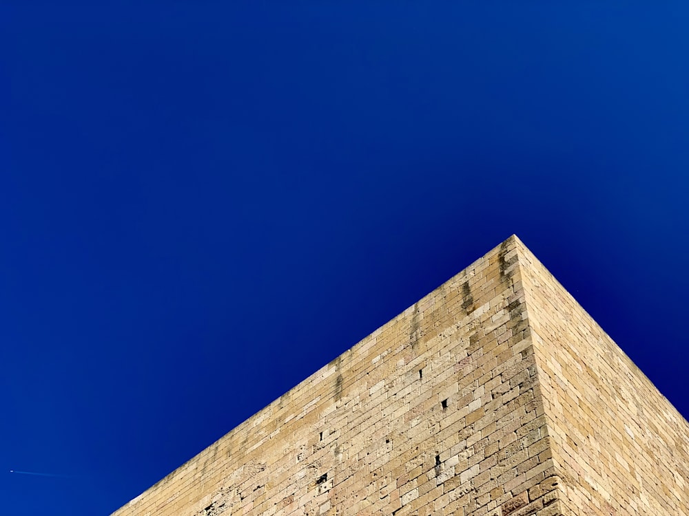 low angle photography of beige bricked building under blue sky