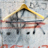 A creativehub hoodie hanging on a rustic hook against a brick wall.