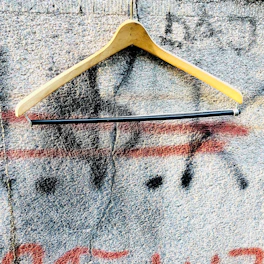 Close-up of a graphic t-shirt with vibrant street art design hanging on a rustic wooden hanger