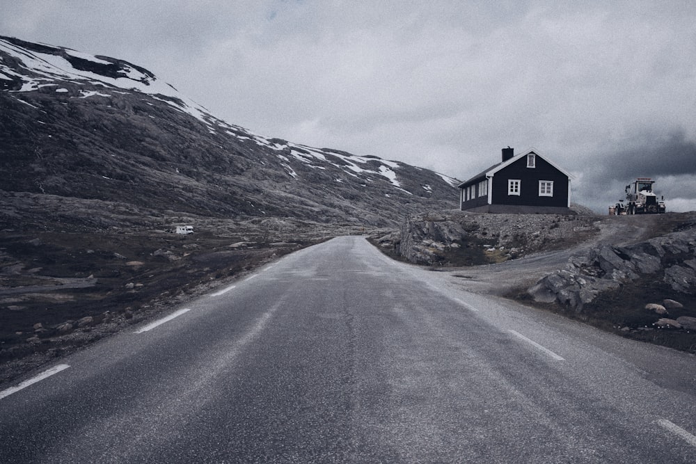 grayscale photo of road beside house