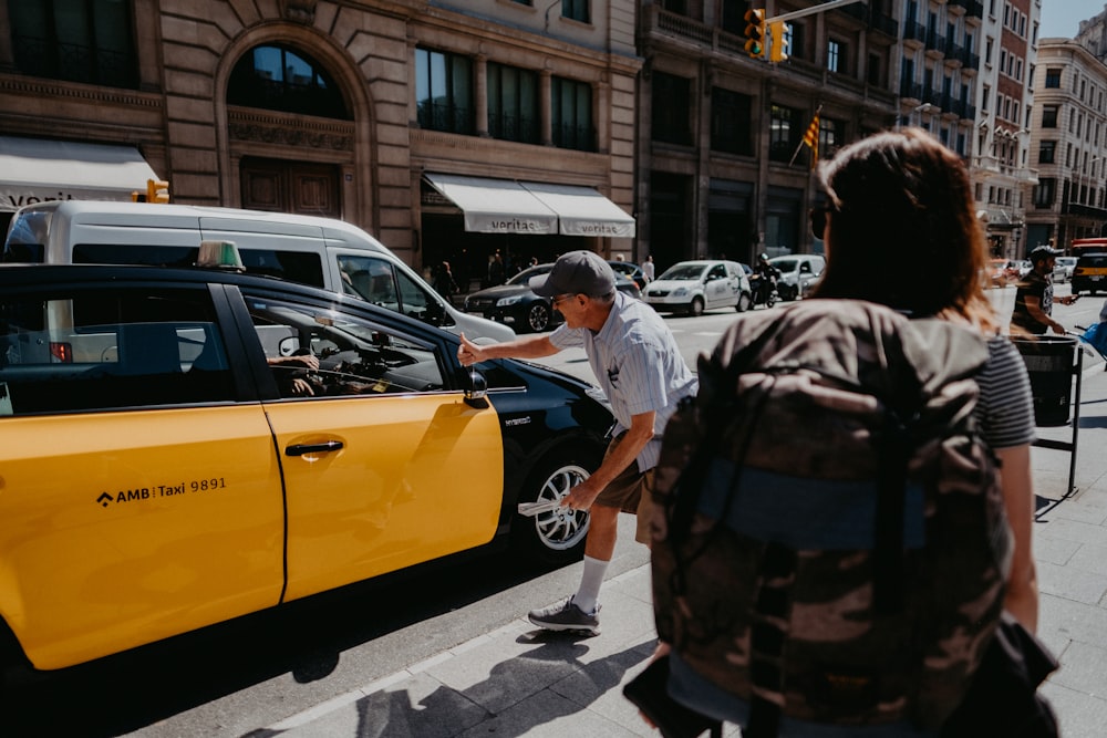 man near yellow and black car