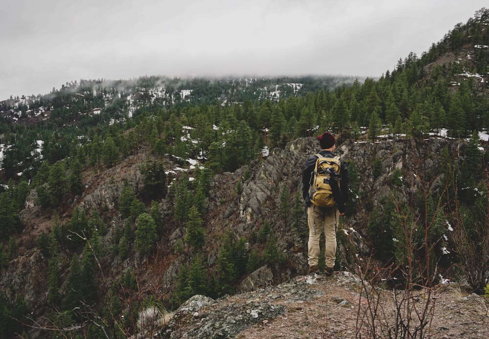 man standing on rocky hill near mountain