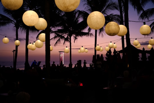 Colorful event lighting casting vibrant glows over a tropical beach party at sunset.