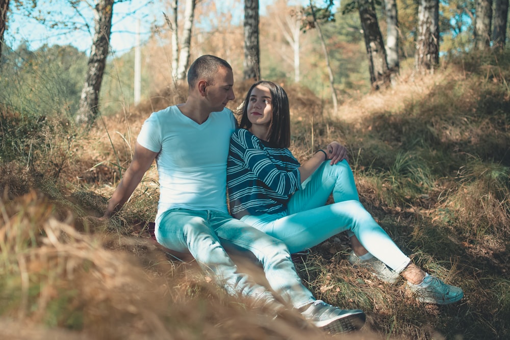 couple sitting on ground near tall trees