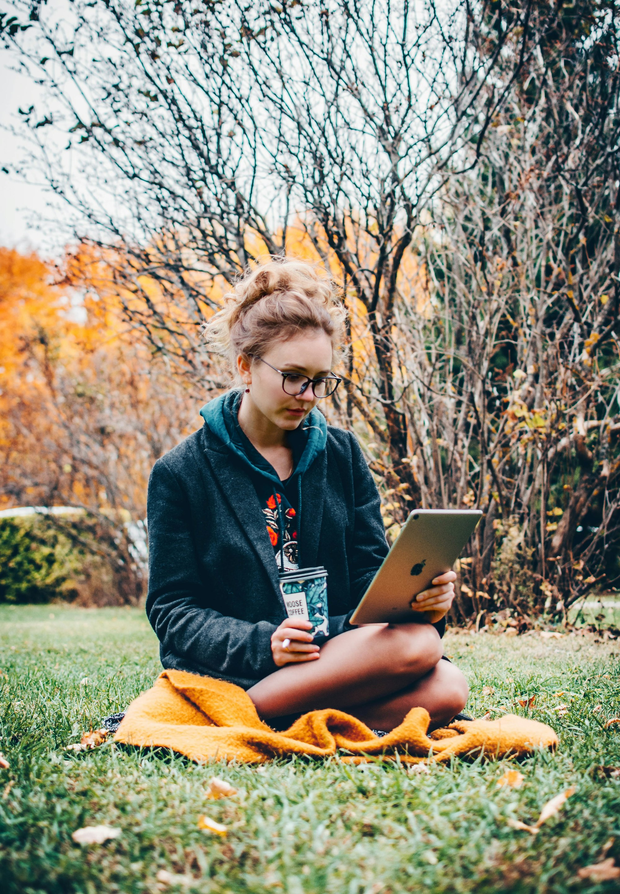 Pessoa sentada num jardim com um iPad na mão esquerda e um copo de café e um Apple Pencil na mão direita.