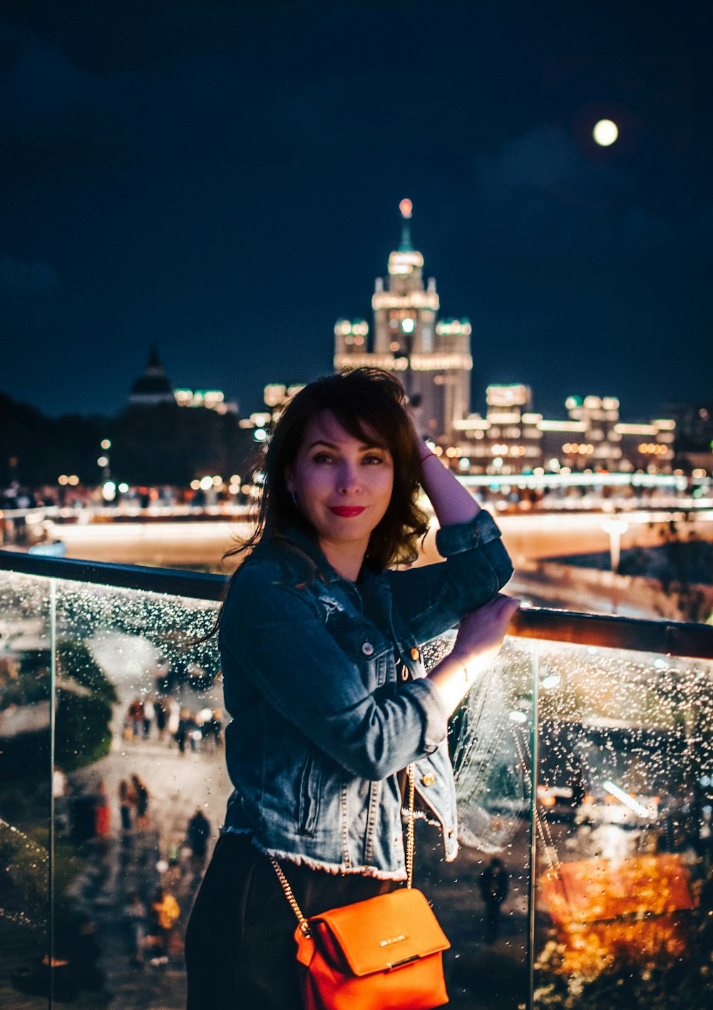 woman left elbow leaning on glass fence during nighttime