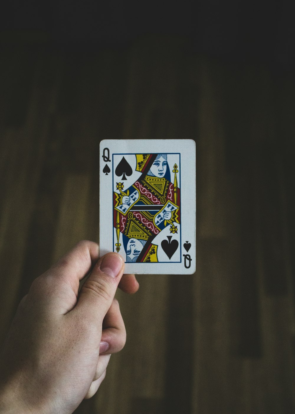 person holding Queen of spade playing card