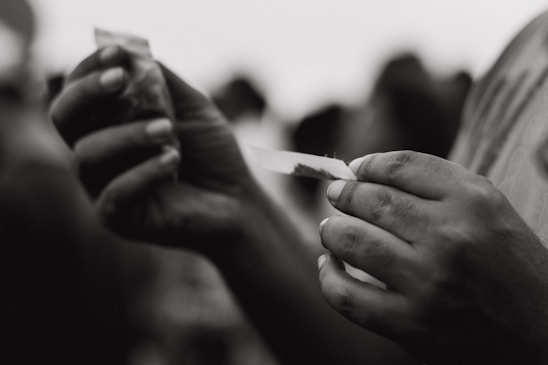 Close-up of a hand rolling a premium handmade cigar with rich tobacco leaves in the background.