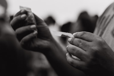 Close-up photo of a hand rolling a cannabis joint with natural light highlighting the textures.