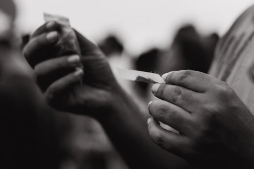 Close-up of Drew Bishop carefully rolling a cigar with tobacco leaves spread out on a wooden table.