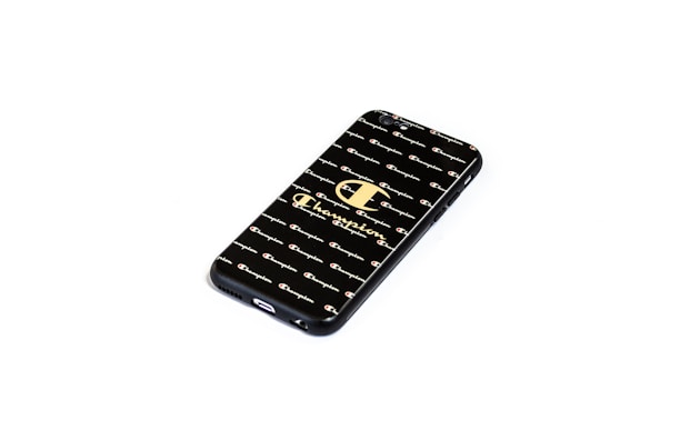 A smartphone case with a black background featuring a pattern of the word 'Champion' repeated across it. The design includes the iconic Champion logo in a larger size in the center.