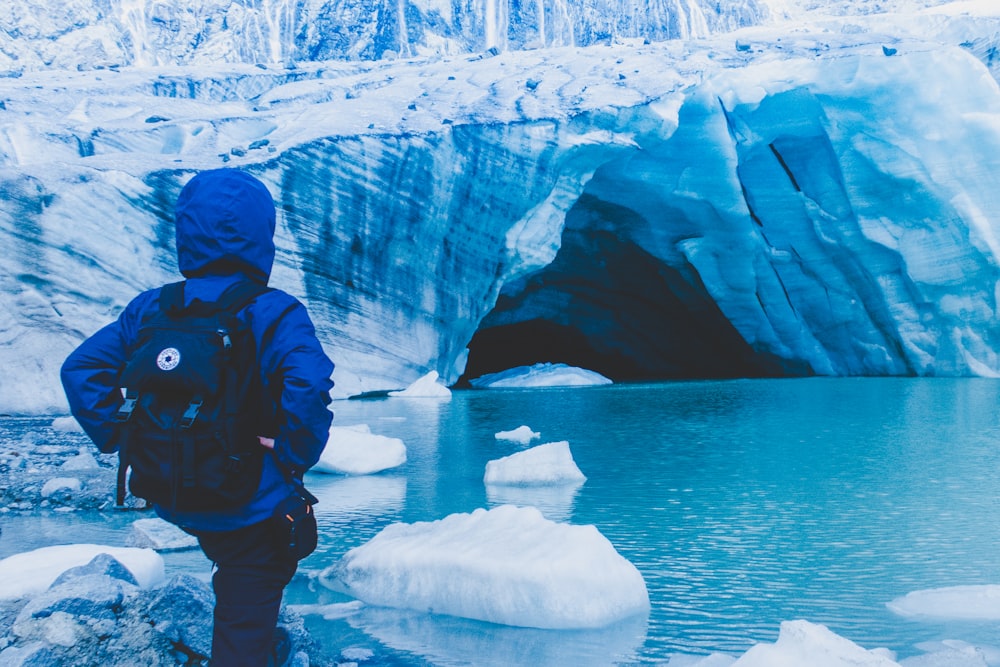 person wearing blue jacket standing near body of water