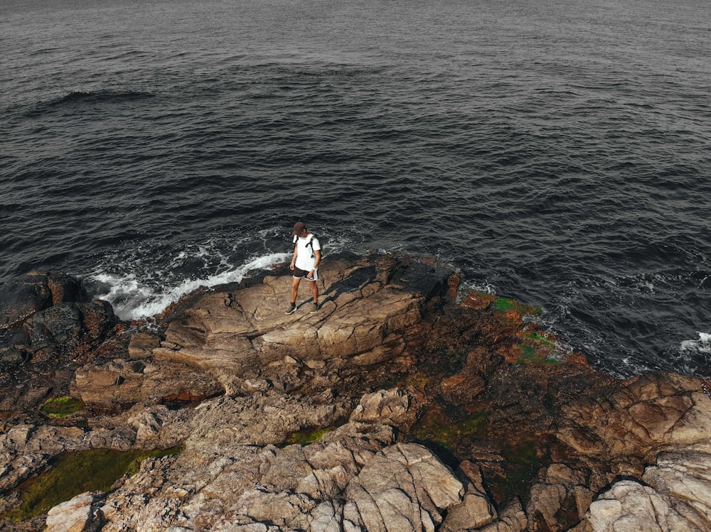 person standing on rocky seashore