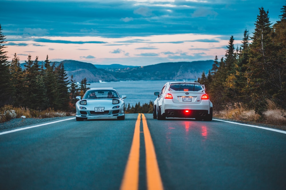 Due auto d'argento e hatchback sulla strada durante il tramonto