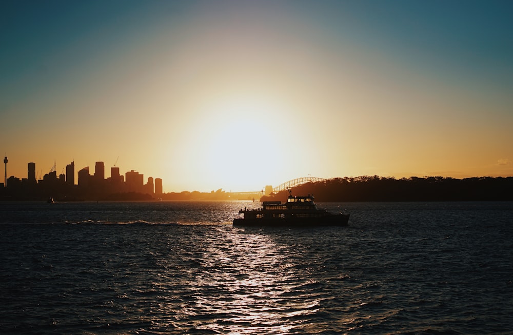 silhouette photography of boat sailing near city