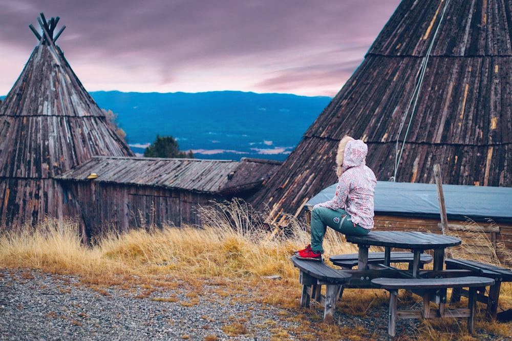 person sitting on brown picnic table outdoors