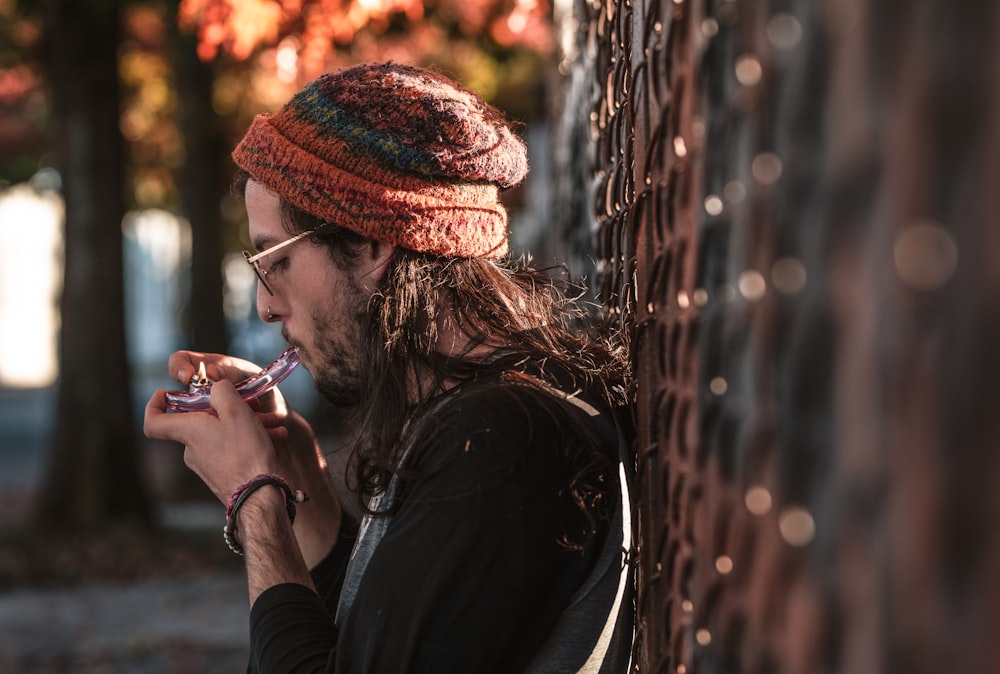 a man with long hair and a knitted hat smoking a cigarette