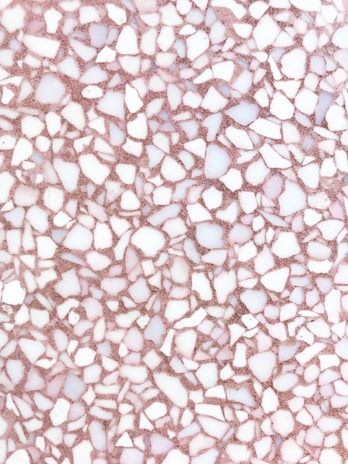 A detailed terrazzo pattern composed of irregular white and light pink stone fragments on a pinkish-brown substrate. The stones are of various shapes and sizes, creating a random, mosaic-like effect.