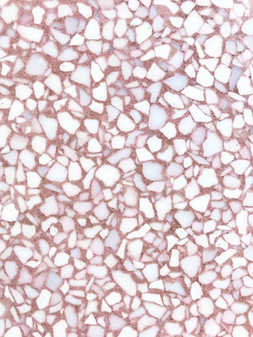 A detailed terrazzo pattern composed of irregular white and light pink stone fragments on a pinkish-brown substrate. The stones are of various shapes and sizes, creating a random, mosaic-like effect.