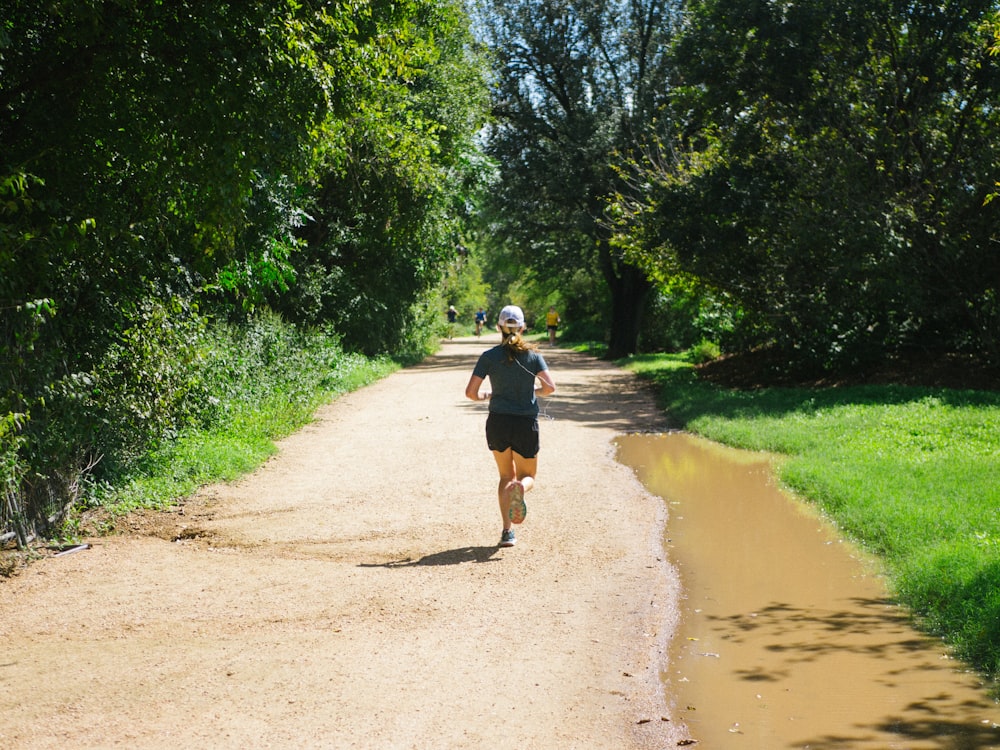 woman in blue shirt running on dirt pathway