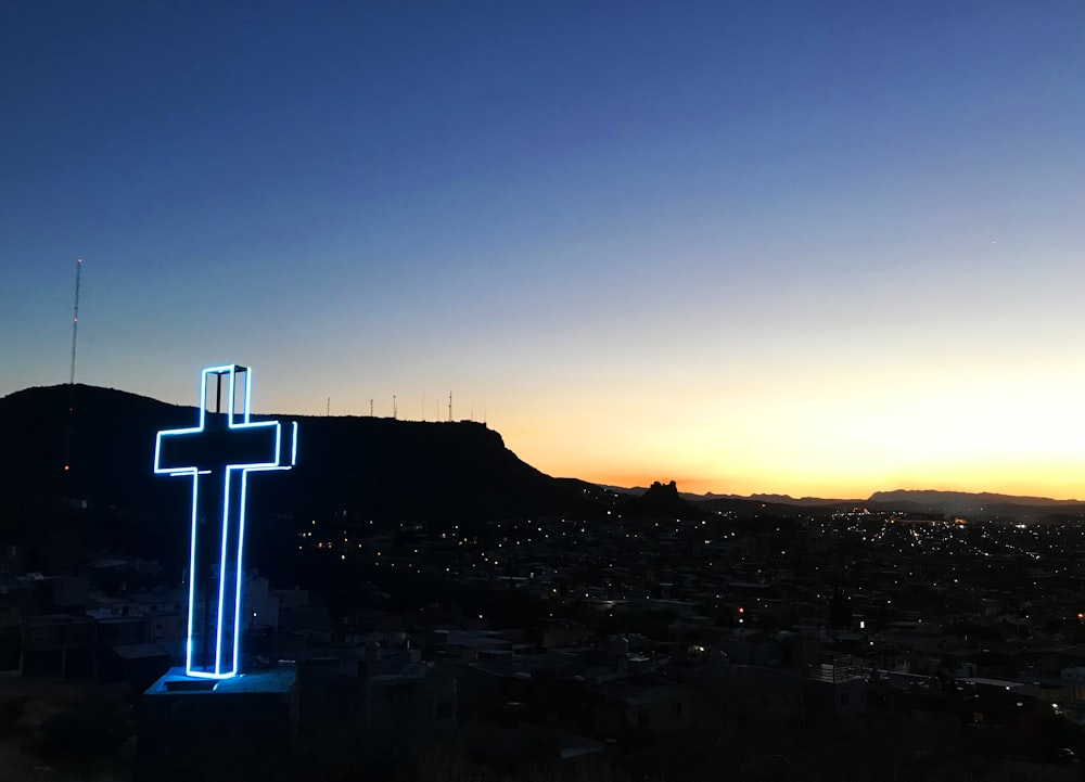 Decoração de cruz iluminada azul durante o nascer do sol