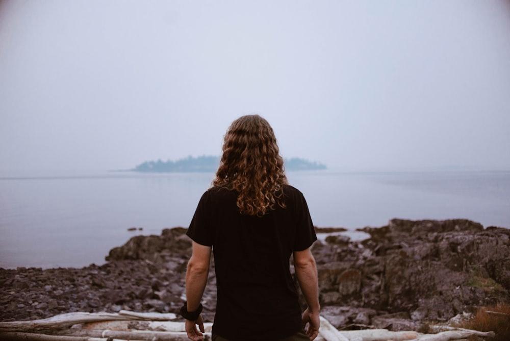 person standing on rocky shore during daytime