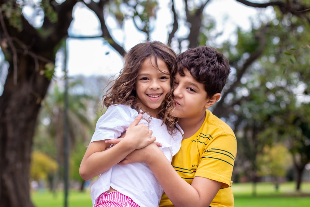 selective focus photography of boy hugging sister
