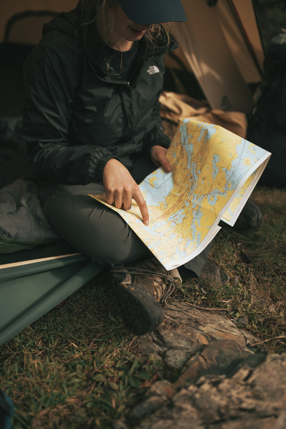 persona que lleva la chaqueta de The North Face sentada en el sofá mientras sostiene el mapa