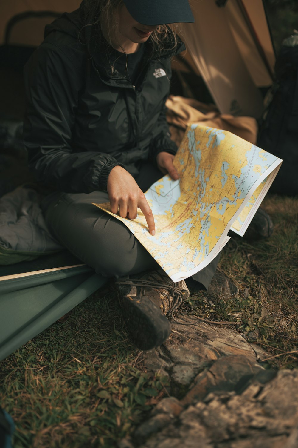 person wearing The North Face jacket sitting on sofa while holding map