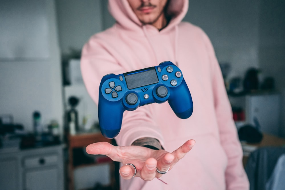 person holding blue Sony PS4 Dualshock 4 c