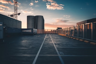 Wide view of a freshly sealed and crack-filled industrial driveway at sunset.