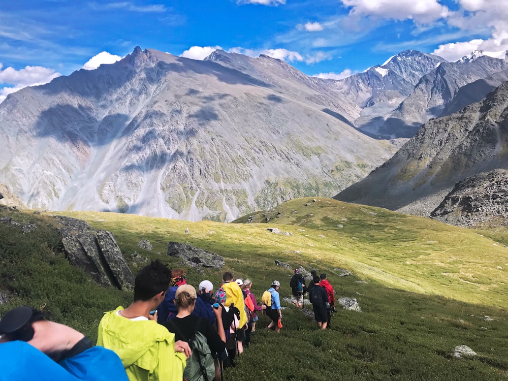 people walking on green mountain during daytim