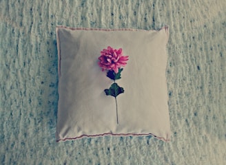Cozy pastel pink cushion with delicate stitching detail on a soft fabric background.
