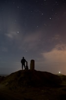 A shadowy figure standing near an ancient stone circle under a starry sky.