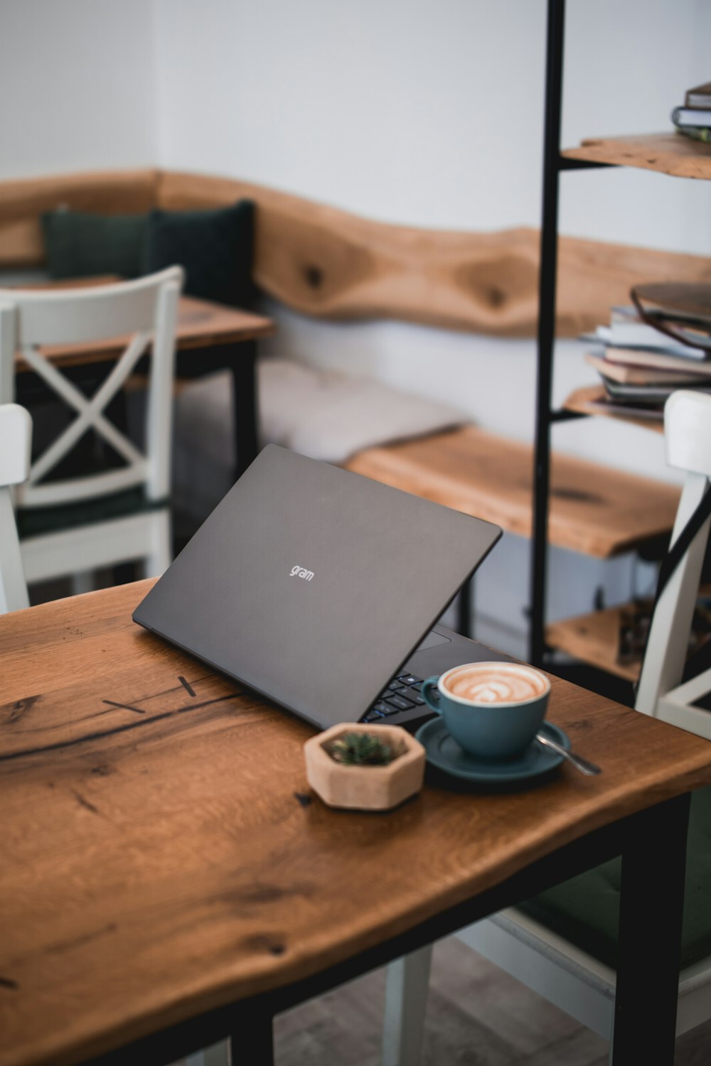 computador portátil preto ao lado da xícara de café