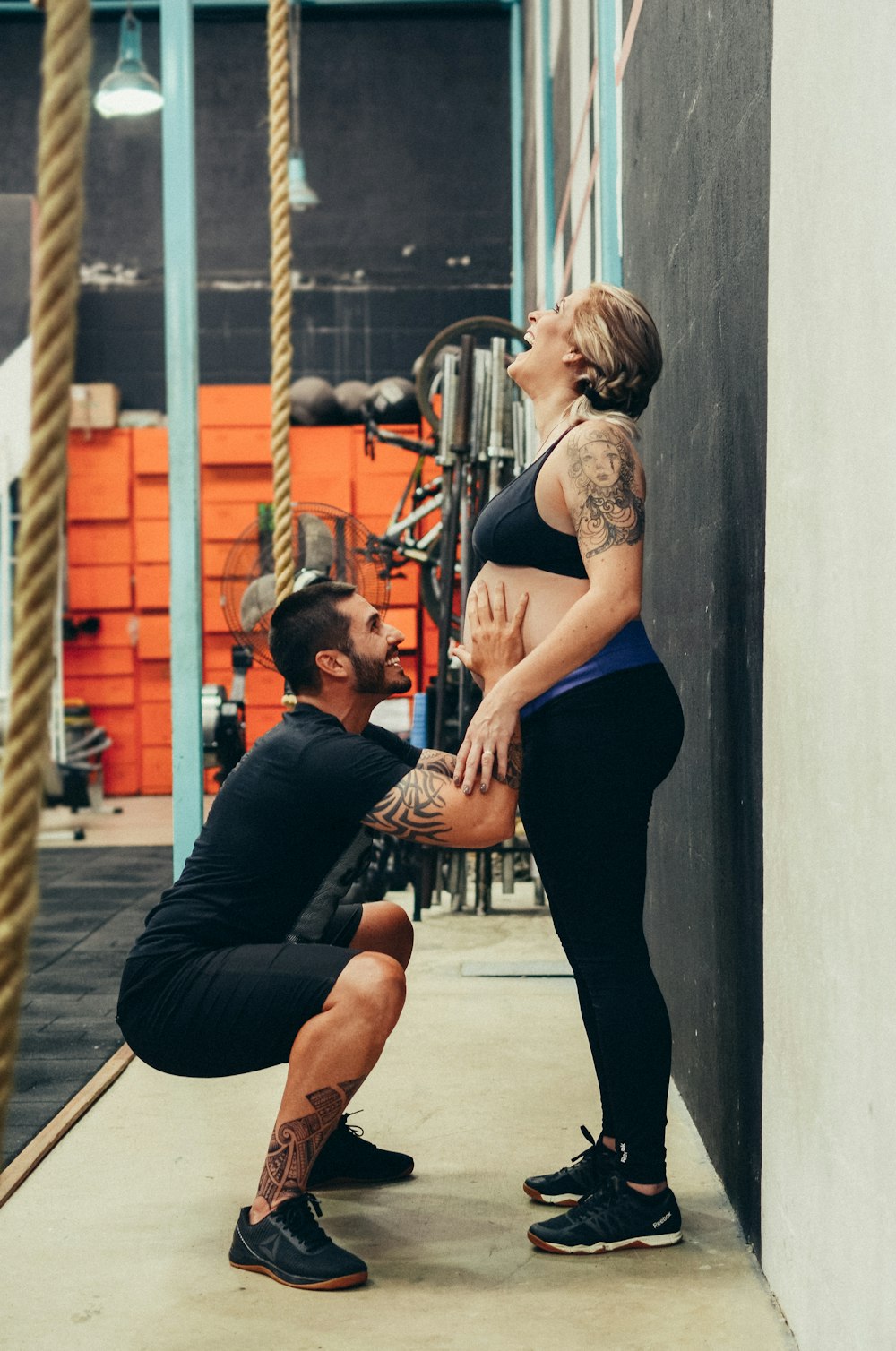 man squatting while touching woman's belly