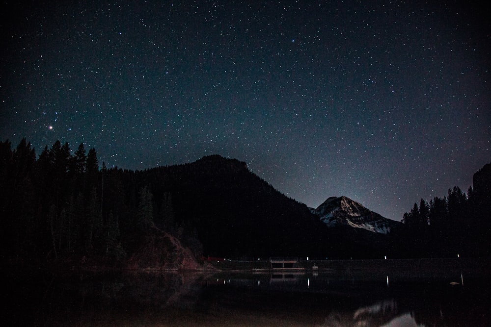 silhouette of mountain near body of water during night