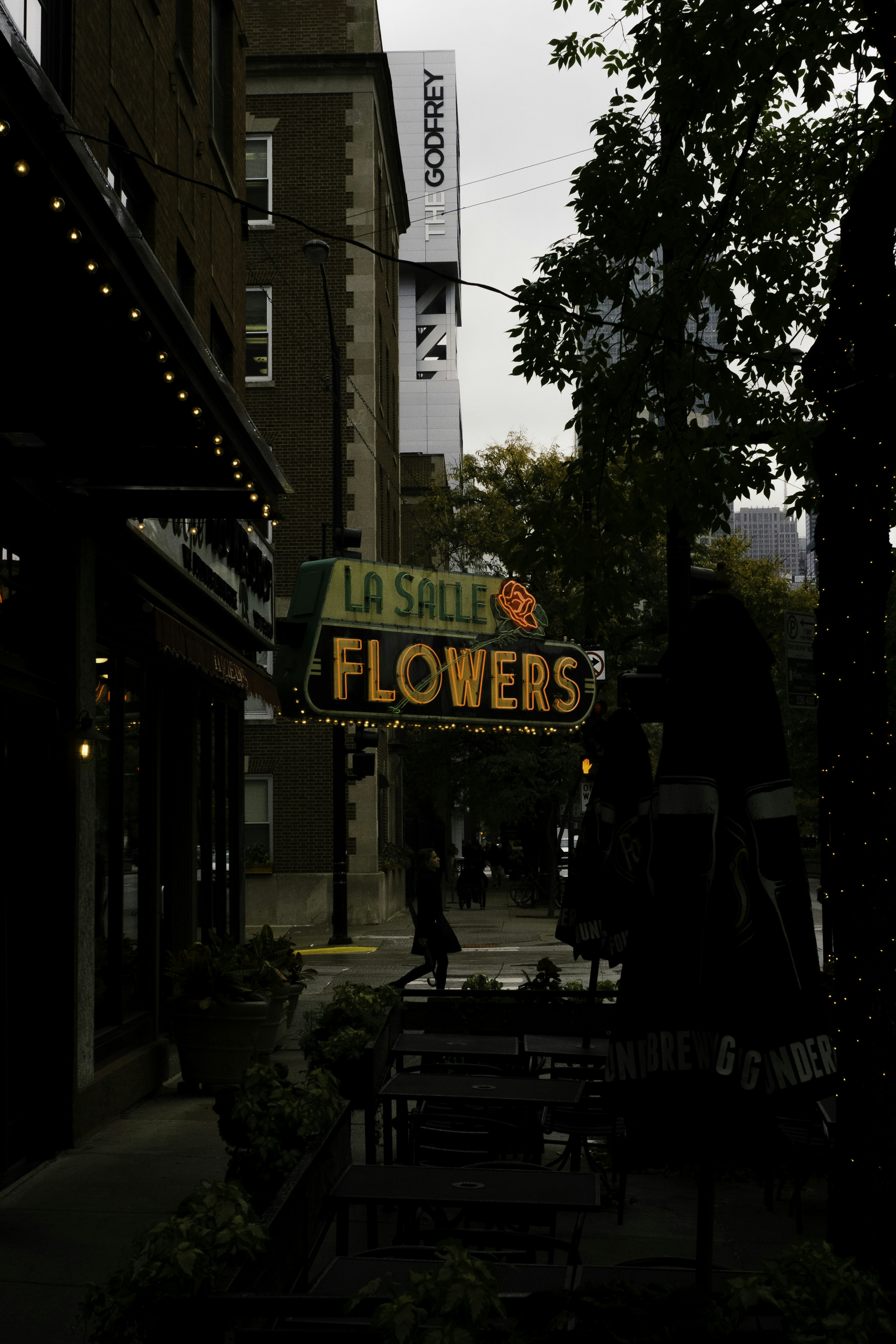 woman walking under La Salle Flowers neon signage