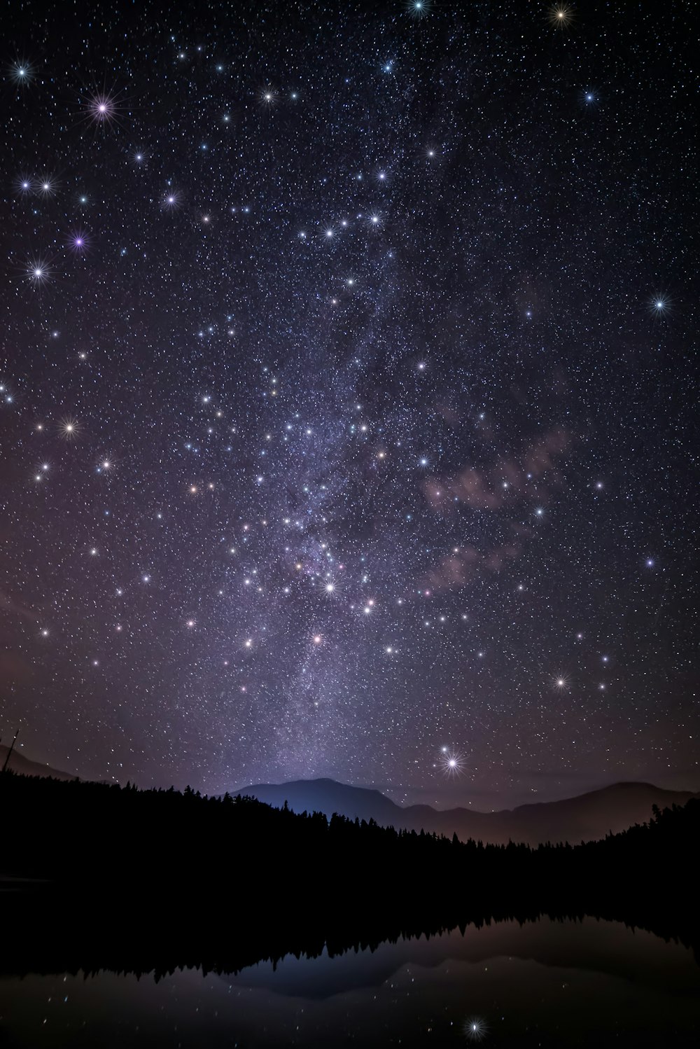 a night sky filled with stars over a lake