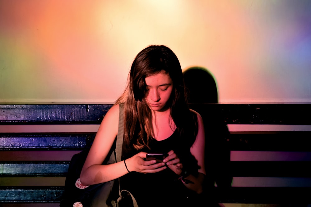 woman wearing black tank dress using smartphone